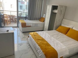 Habitación de hotel con dos camas, un escritorio y vistas a la calle.