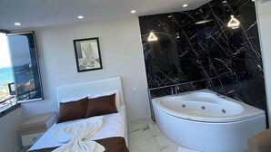 A modern bedroom with a large bed, a bathtub, and a view of the sea. - BeyazmotelRestaurant (Erdemli)