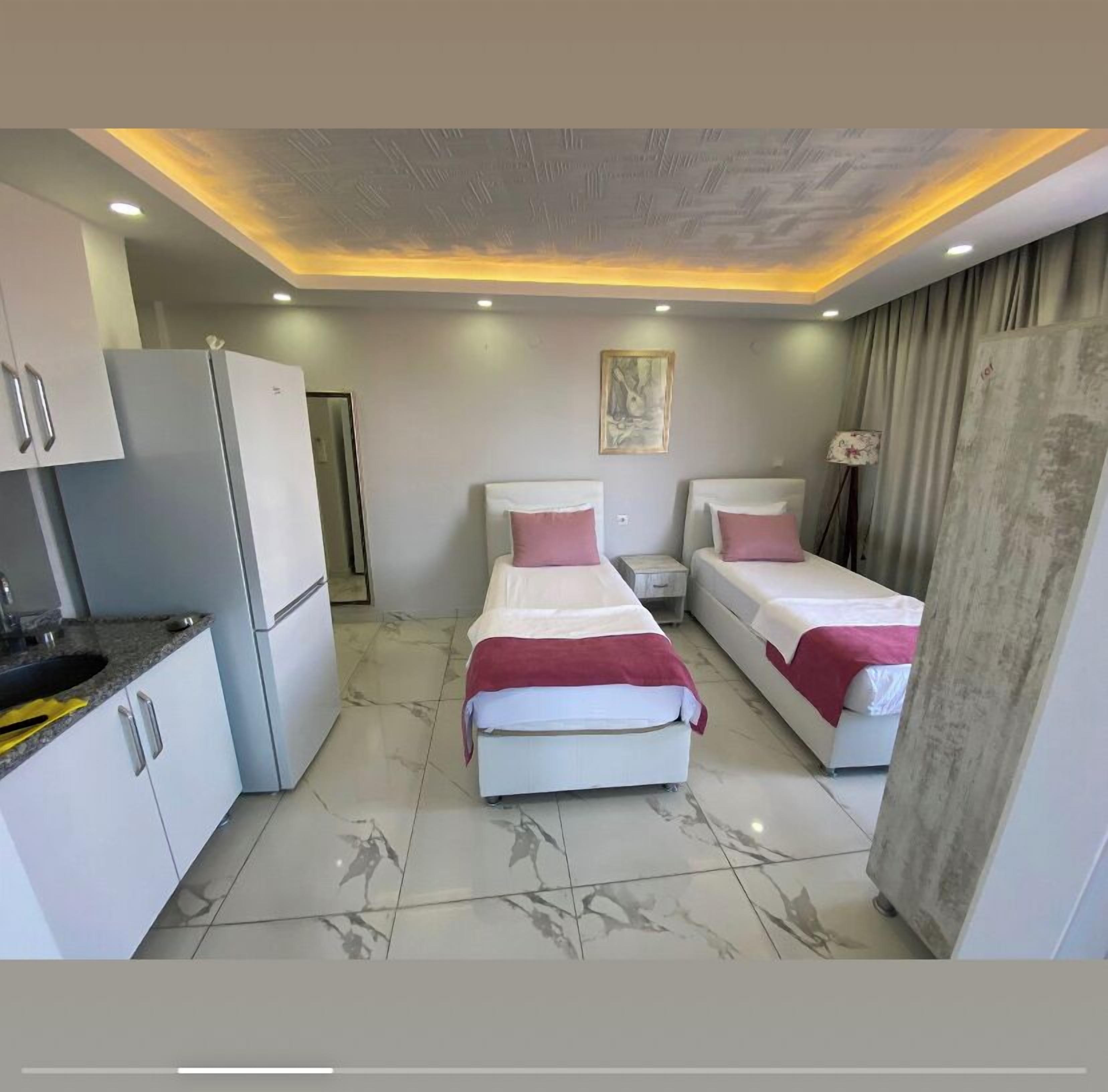 Une chambre d’hôtel de taille réduite, comprenant deux lits, une kitchenette et une salle de bain.