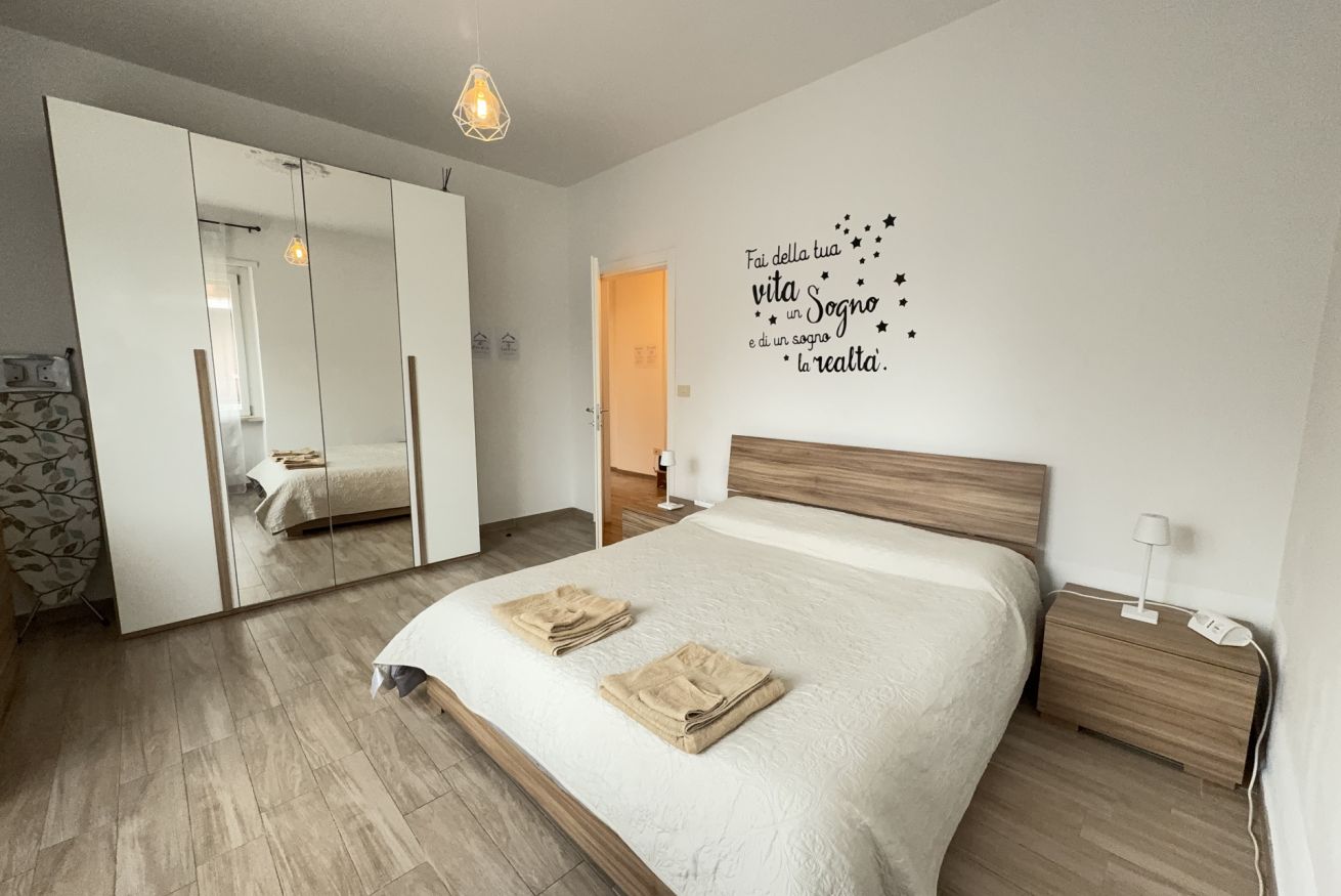Une chambre à coucher comprenant un lit, une table de chevet, une lampe de chevet, un miroir et un mur orné d’une citation inspirante.
