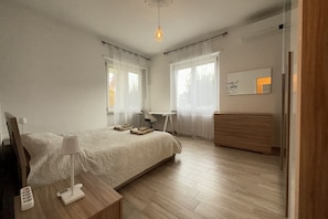 A modern bedroom with a bed, bedside table, lamp, and a desk with a chair. - Private Parking, with a View of the Alba Hills (Alba)