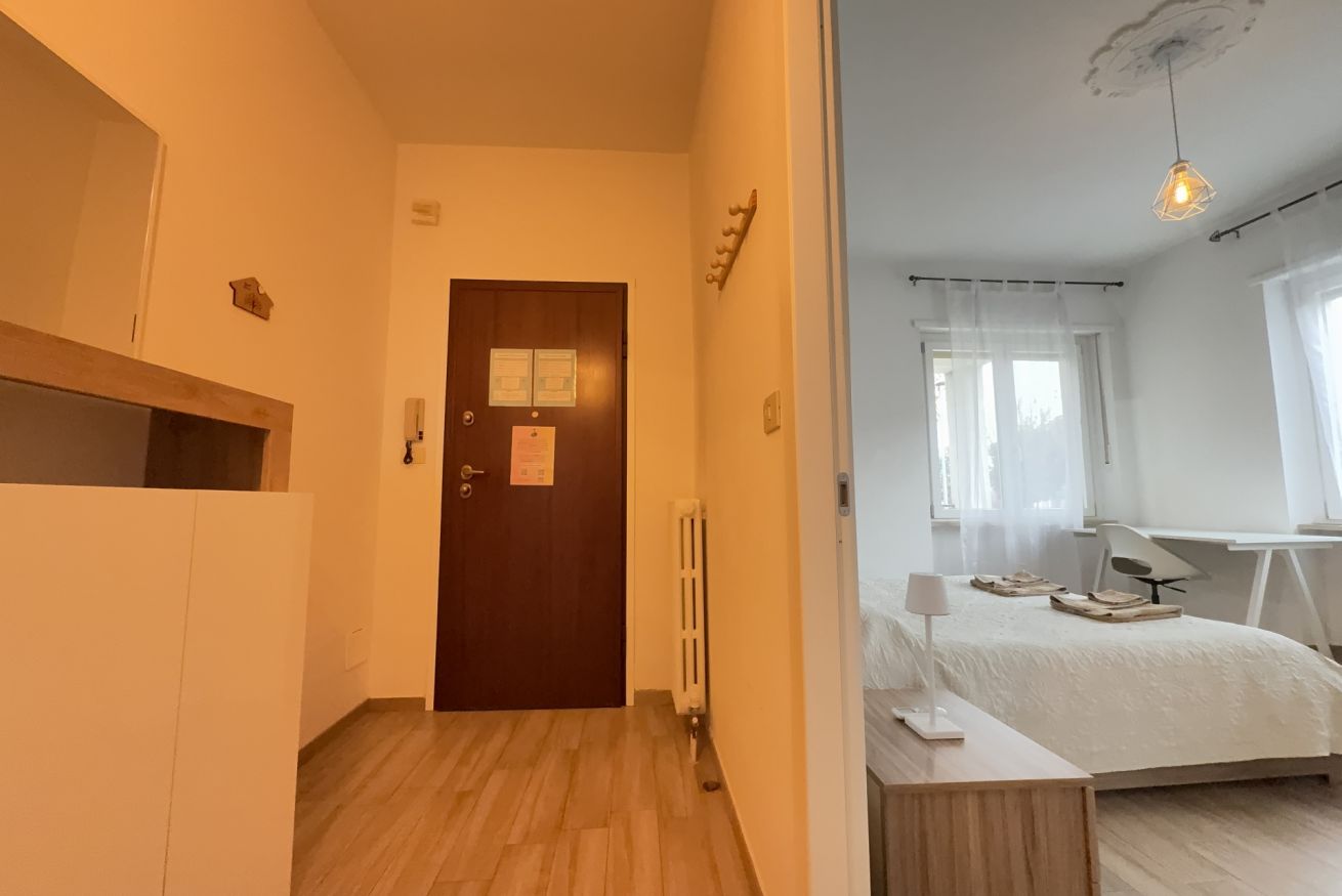 Una camera da letto con un letto, un comodino, una lampada e una scrivania con una sedia.