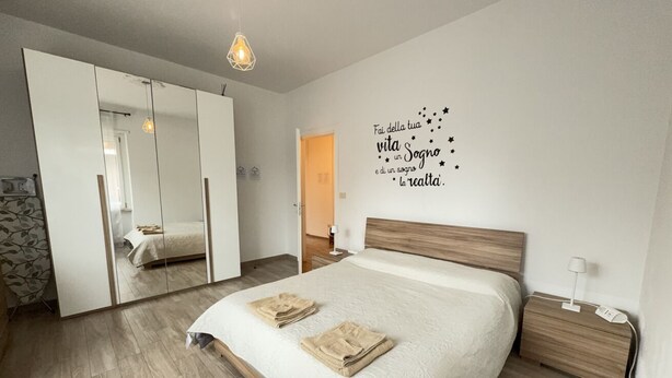 Une chambre à coucher comprenant un lit, une table de chevet, une lampe de chevet, un miroir et un mur orné d’une citation inspirante.