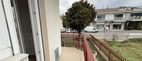 A balcony with a tiled floor, a red railing, and a tree.