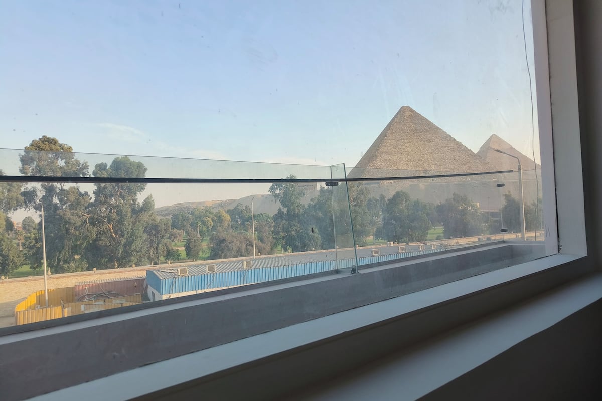 A view from a window overlooking a train station with a pyramid structure in the background.