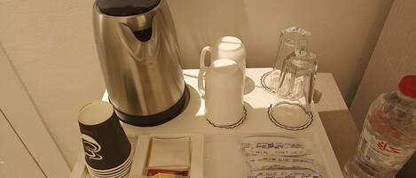 A tray with a coffee maker, cups, sugar packets, and a water bottle.