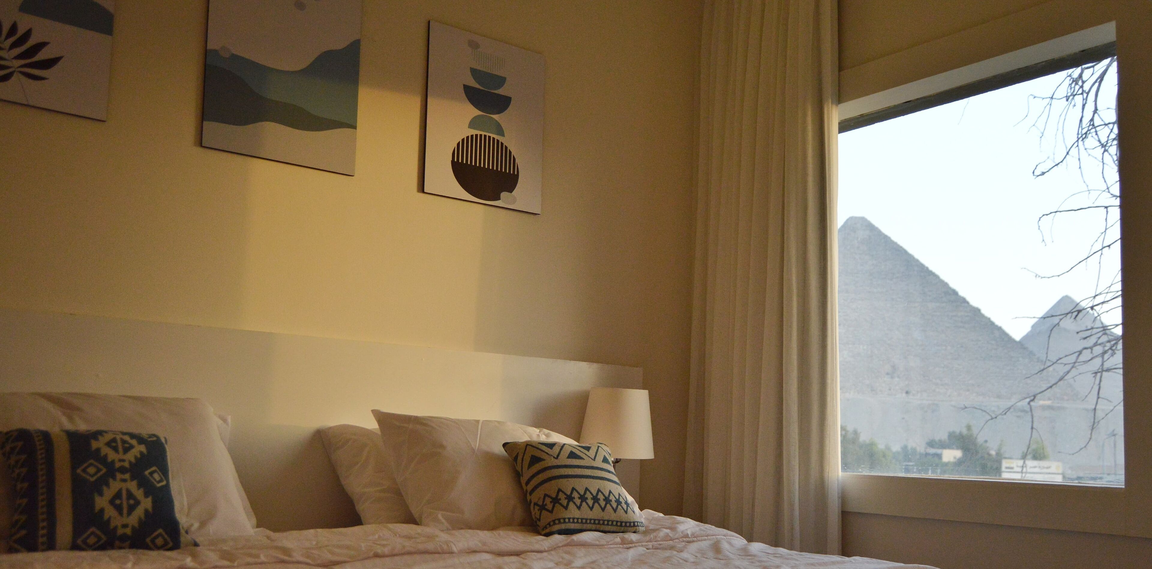 Une chambre d’hôtel avec un lit, des oreillers, une fenêtre donnant sur une vue sur la montagne et des œuvres d’art murales.