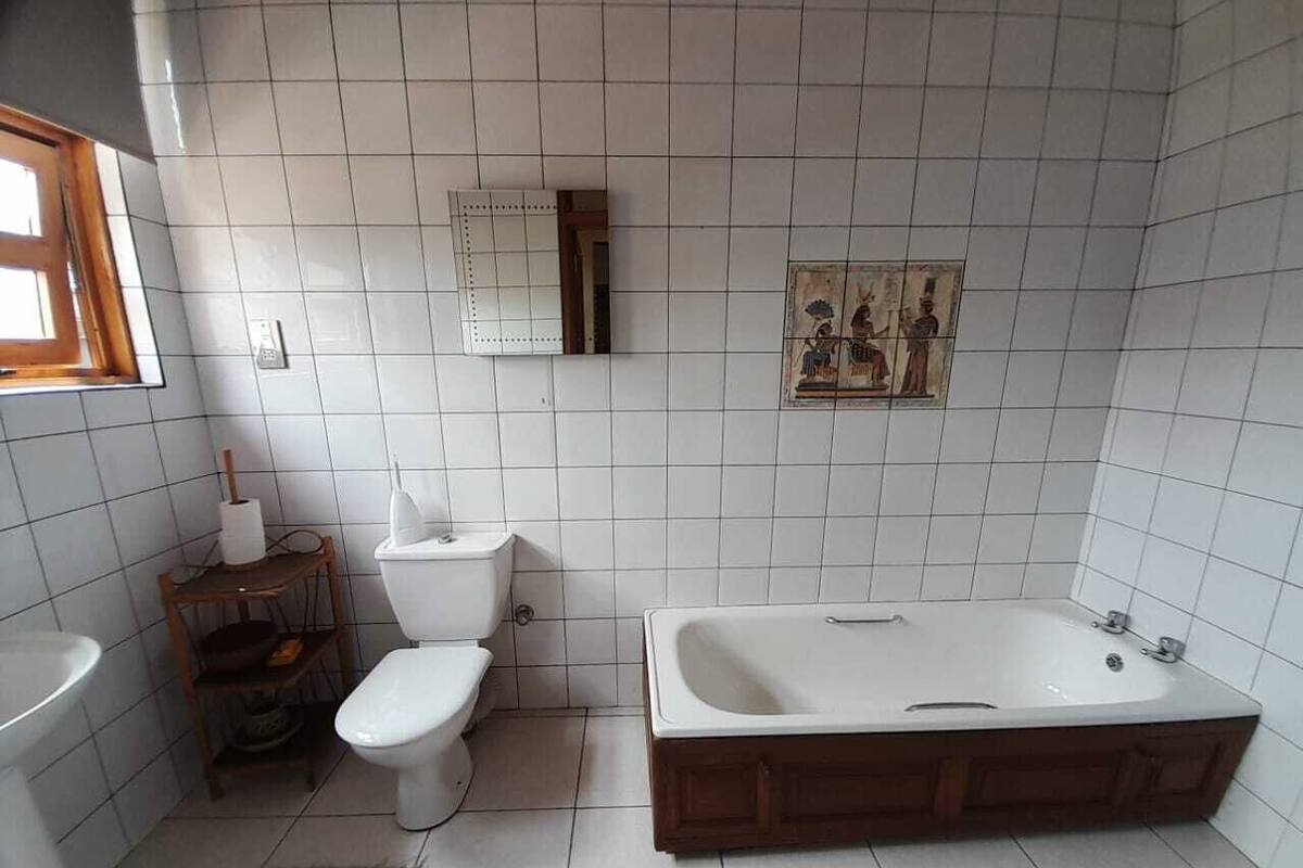 Kylpyhuone, jonka seinät on päällystetty valkoisilla laatoilla, ja jossa on wc, pesuallas ja kylpyamme.