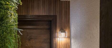 A wooden door with a textured wall and a light fixture to the right.