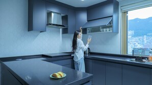 Een moderne keuken met een groot eiland, donkere kastjes en uitzicht op de stad door het raam.