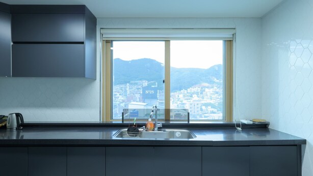 Een moderne keuken met een groot raam, een spoelbak en een waterkoker op het aanrecht.