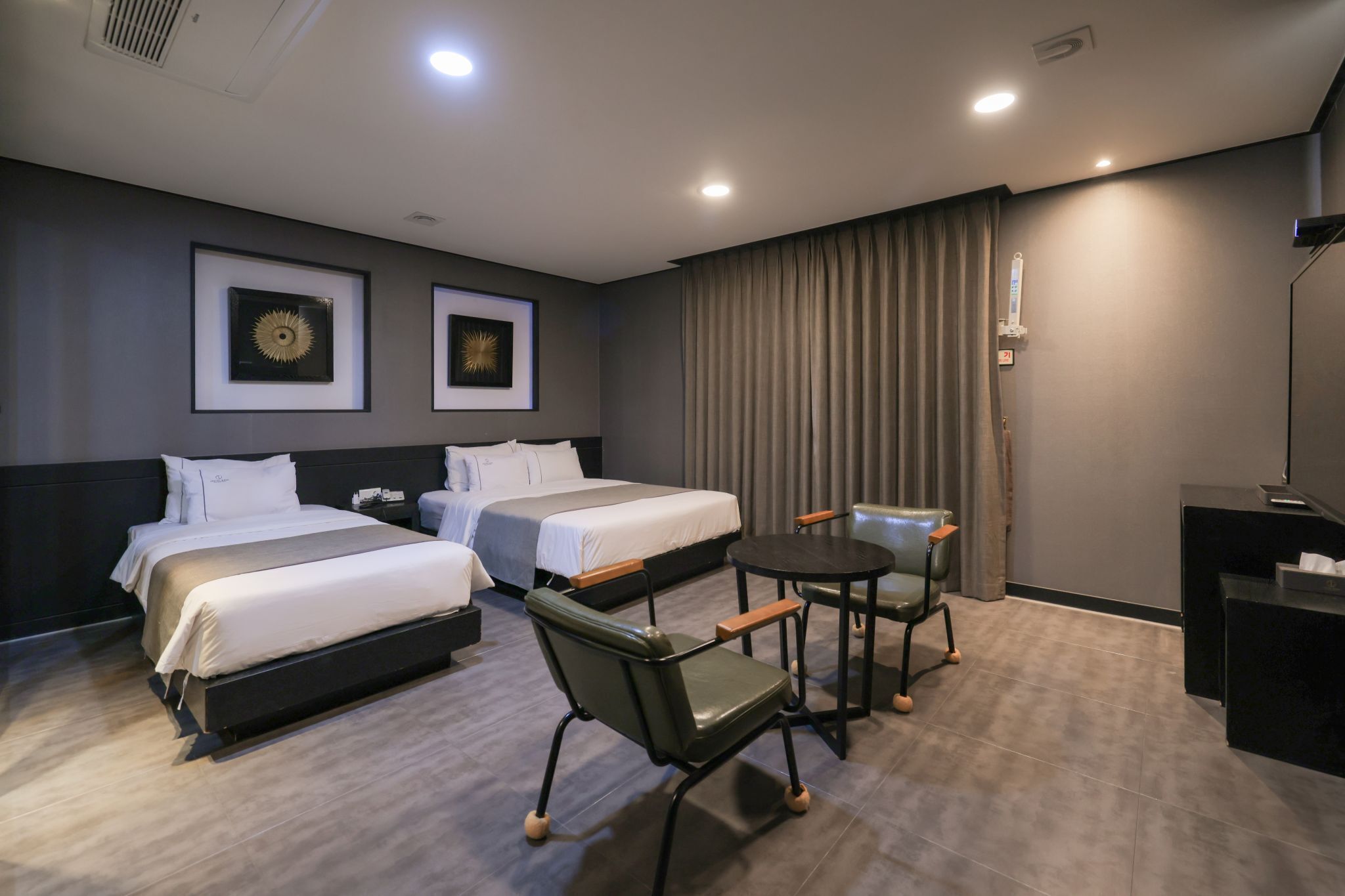 Une chambre d’hôtel avec deux lits, un bureau, une chaise et une petite table.