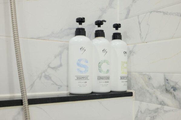 Three bottles of shampoo, conditioner, and body wash on a bathroom shelf. - Yeosu ZAVA Hotel (Yeosu)
