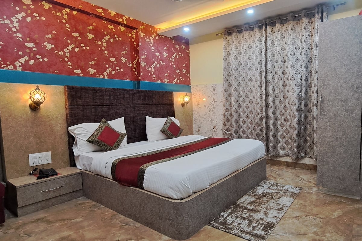 A hotel room with a bed, bedside table, and a desk with a chair.