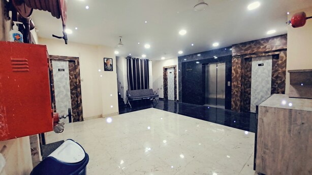 A hotel lobby with a marble floor, a red locker, an elevator, and a bench. - RS Residency By Wheels Hospitality (Varanasi)