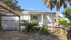 A white house with a porch, a wooden fence, and a palm tree. - Vintage Waves (Panama City Beach)