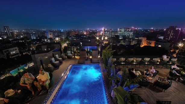 A rooftop pool area with a view of the city at night. - May De Ville Corner Hotel (Hanoi)