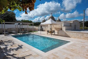 Una piscina con sillas de descanso y un edificio de piedra con tejados cónicos.