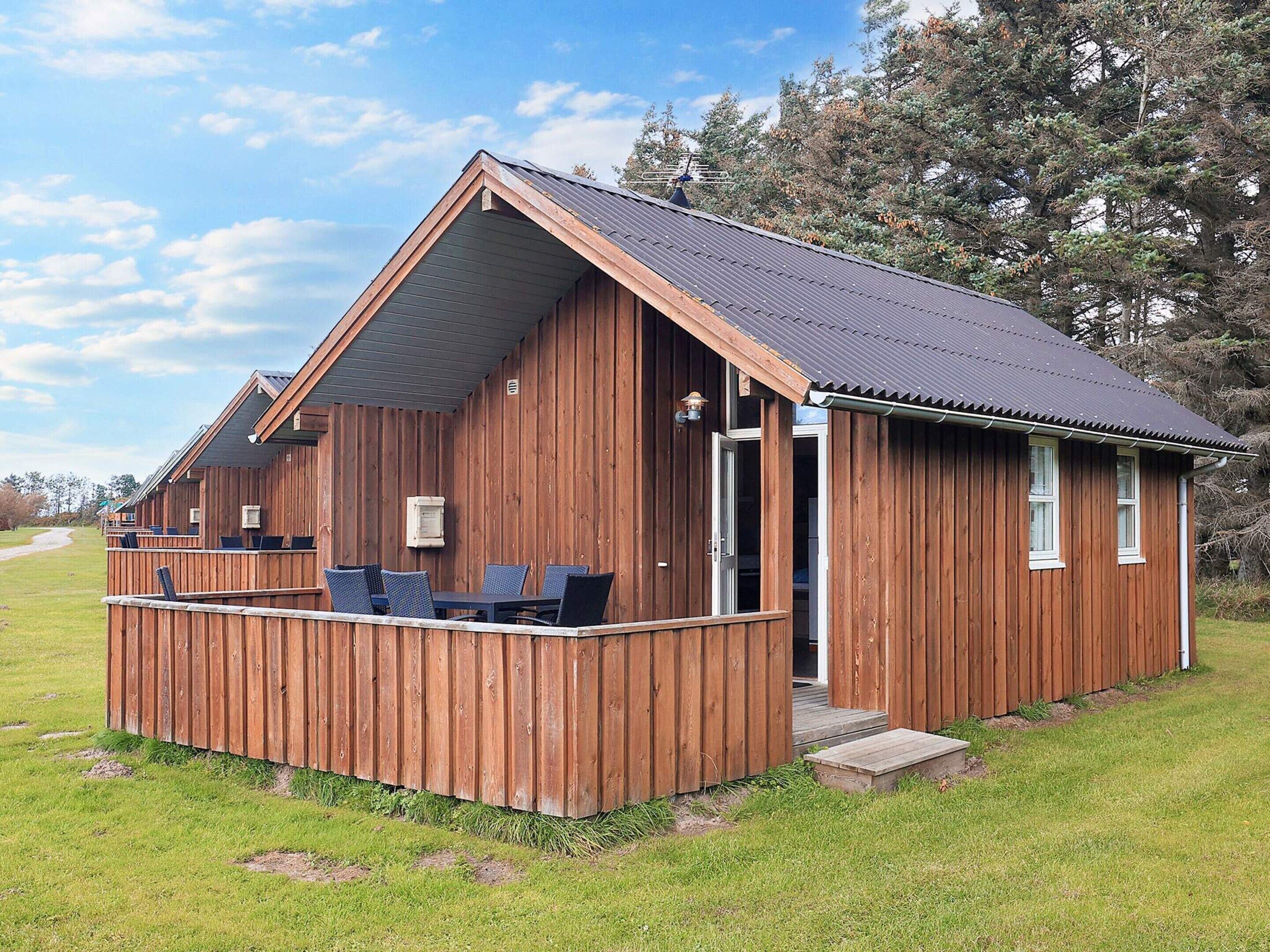 A wooden cabin with a balcony, a door, and a window.