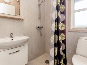 Un bagno con lavandino bianco, doccia e water.
