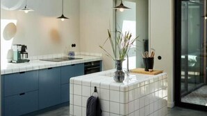 Et moderne køkken med ovenlys, hængende lamper og en central ø med en vase og plante.