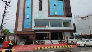 Een hotel genaamd 'Hotel Dwarka' met een modern design, herkenbaar aan een opvallend bord en een trap die naar de ingang leidt.