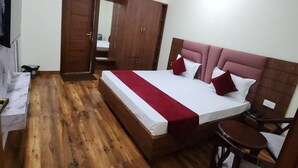 Een slaapkamer met houten vloer, een bed met een rood-wit dekbedovertrek, een plafondventilator en een kledingkast.