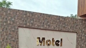 Naamplaatje voor 'Motel Dwarika', met een bakstenen muur op de achtergrond en bloempotten ervoor.