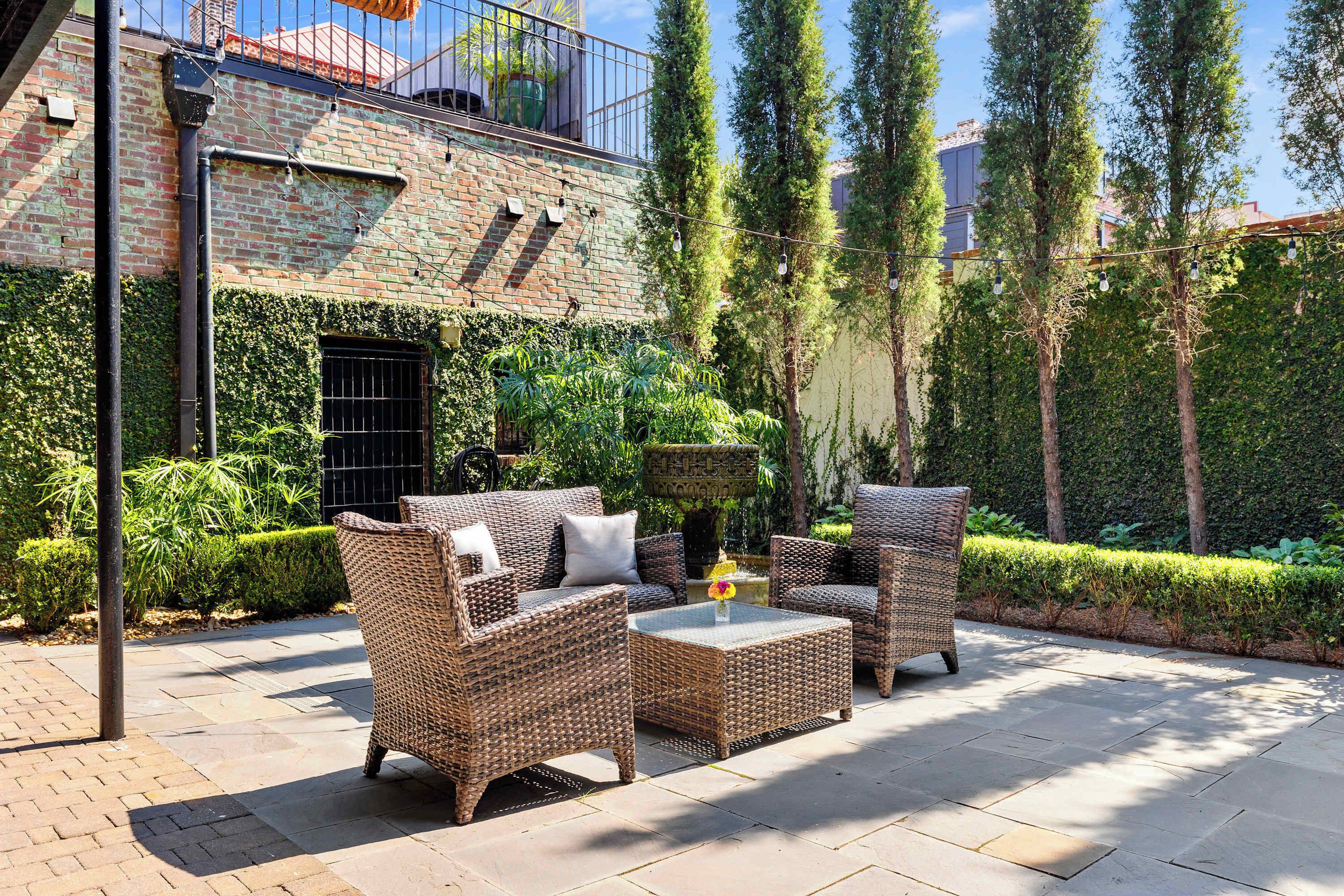 An outdoor patio with wicker furniture, a small table, and a potted plant.