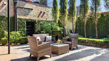 An outdoor patio with wicker furniture, a small table, and a potted plant.