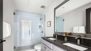 A modern bathroom with a glass-enclosed shower, a white toilet, and a double sink vanity. - Fire Tower | Cozy Downtown Charleston Studio! (Charleston)