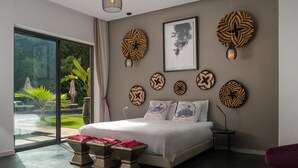 A modern bedroom with a large bed, a glass door leading to a garden, and decorative wall art. - NETUMIA (Marrakech)