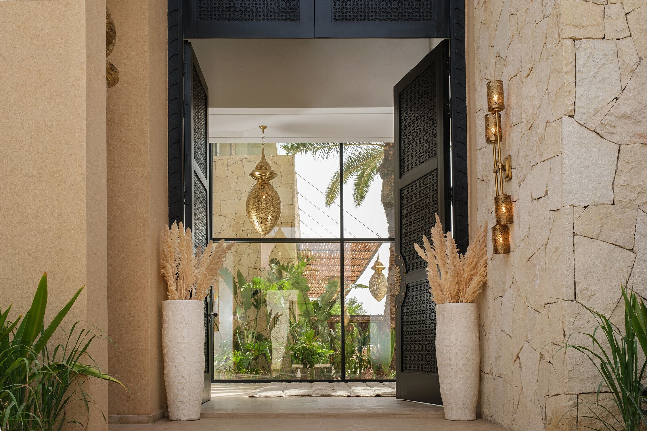 A modern entrance with a stone wall, a glass door, and potted plants.