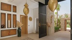 A modern interior with a wooden wall panel, a large black door, and a view of palm trees outside. - EYLINE - luxurious villa with SPA on the Amelkis Golf course near Marrakech (Marrakech)