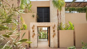 A building entrance with a stone archway, a black door, and a view into a lush indoor garden. - EYLINE - luxurious villa with SPA on the Amelkis Golf course near Marrakech (Marrakech)