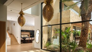 A modern interior with a staircase leading to a kitchen, a dining area, and a large glass wall with a view of a landscaped garden. - EYLINE - luxurious villa with SPA on the Amelkis Golf course near Marrakech (Marrakech)