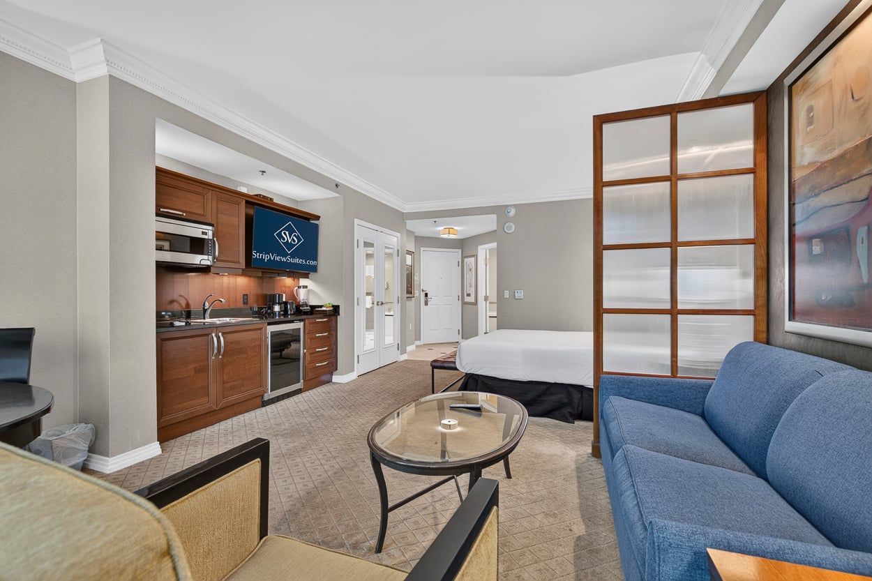 Une chambre d’hôtel équipée d’une kitchenette, d’un lit, d’un canapé et d’une table basse en verre.