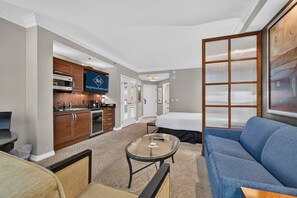 A hotel room with a kitchenette, a bed, a sofa, and a glass coffee table. - Strip View Studio • Balcony • No Resort Fee C17T3 (Las Vegas)