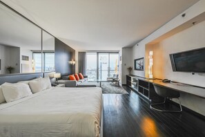 A modern hotel room with a large bed, a desk, a TV, and a view of the city. - Strip View Studio • Balcony • No Resort Fee • Free Parking • TI24 (Las Vegas)