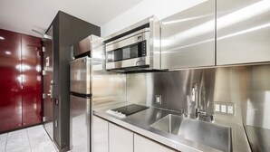 A modern kitchen with stainless steel appliances, a built-in microwave, and a double sink. - SVS: Strip View Studio | Open Balcony | Full Size Fridge | Palms Place (Las Vegas)