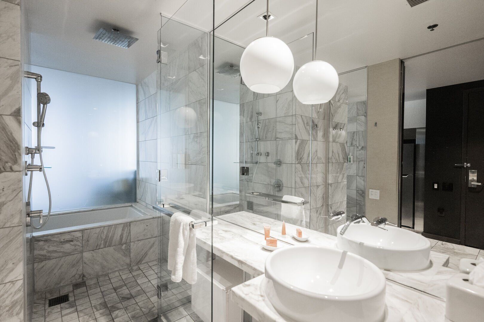 A modern bathroom with a glass-enclosed shower, two sinks, and a large mirror.