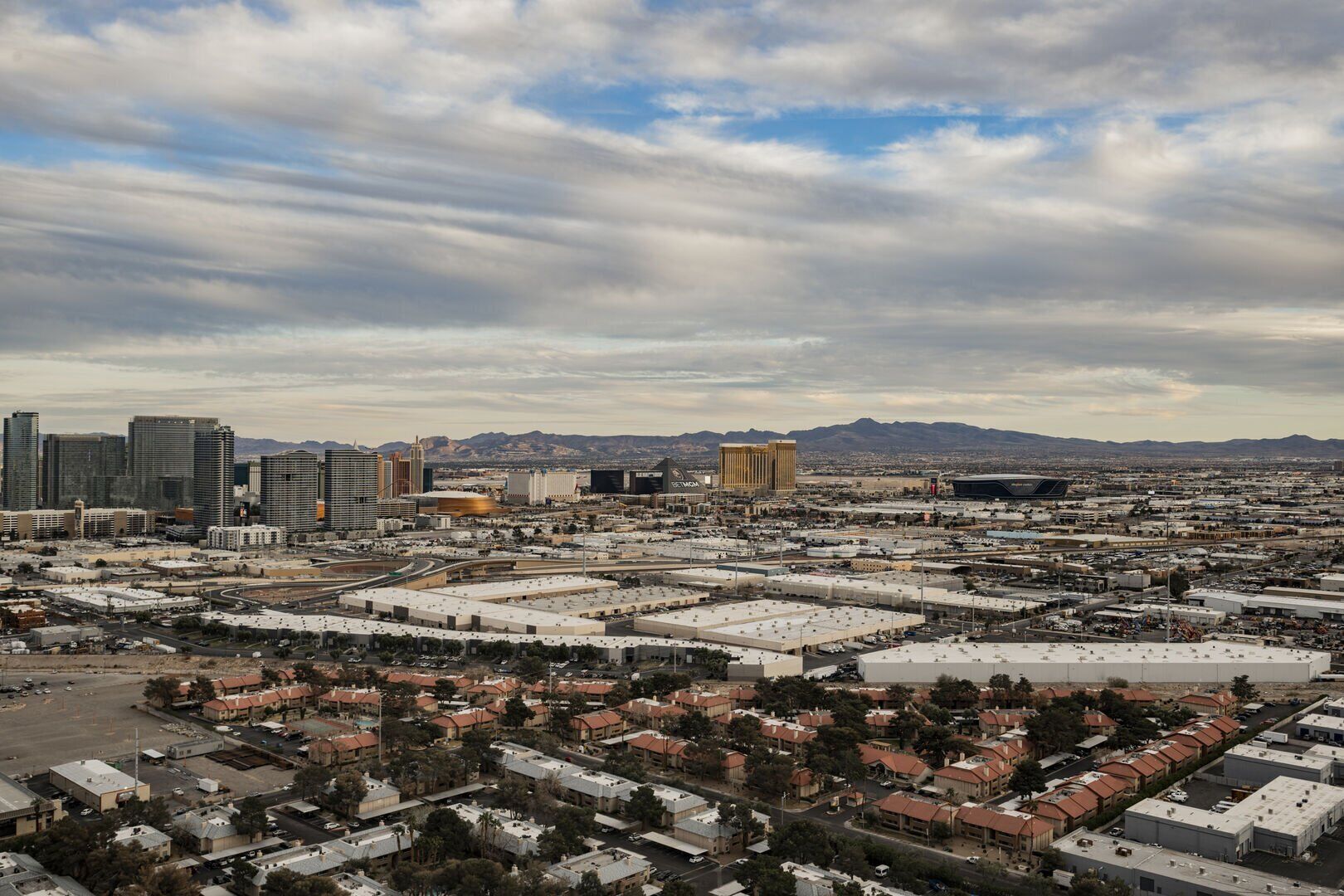 A cityscape with a mix of residential and commercial buildings, including high-rise structures and a large stadium.