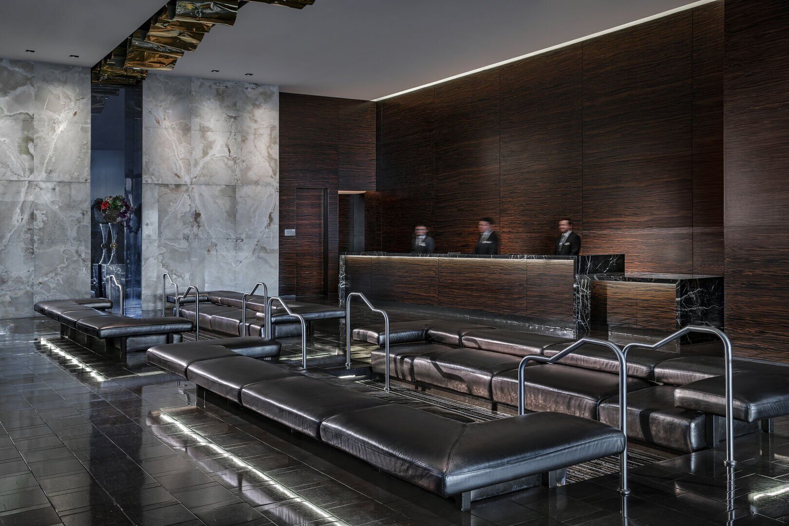 A modern lobby with a reception desk, leather seating, and a marble wall.