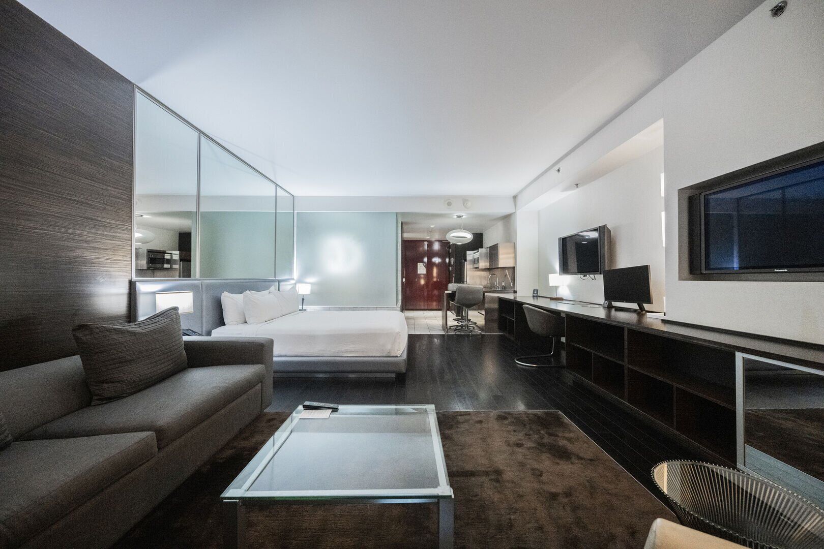 Ein modernes Hotelzimmer mit einem großen Bett, einer Couch, einem Couchtisch, einem Fernseher und einem Essbereich.
