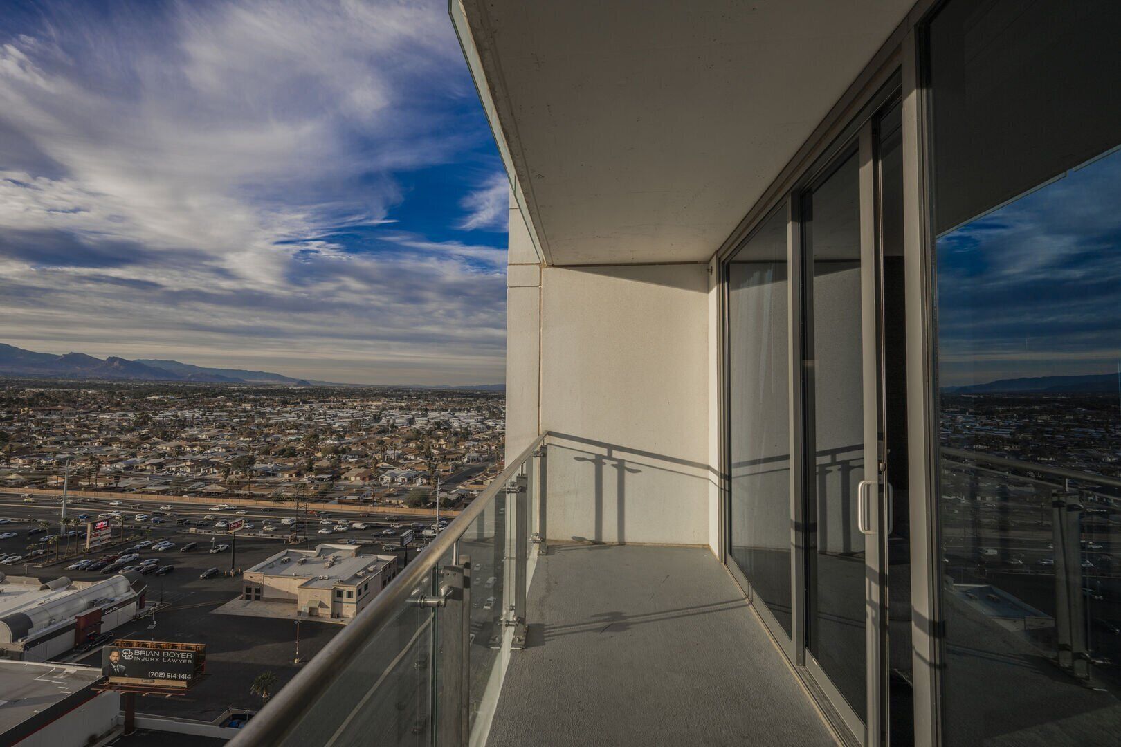 A balcony with a city view, a glass door, and a metal railing.