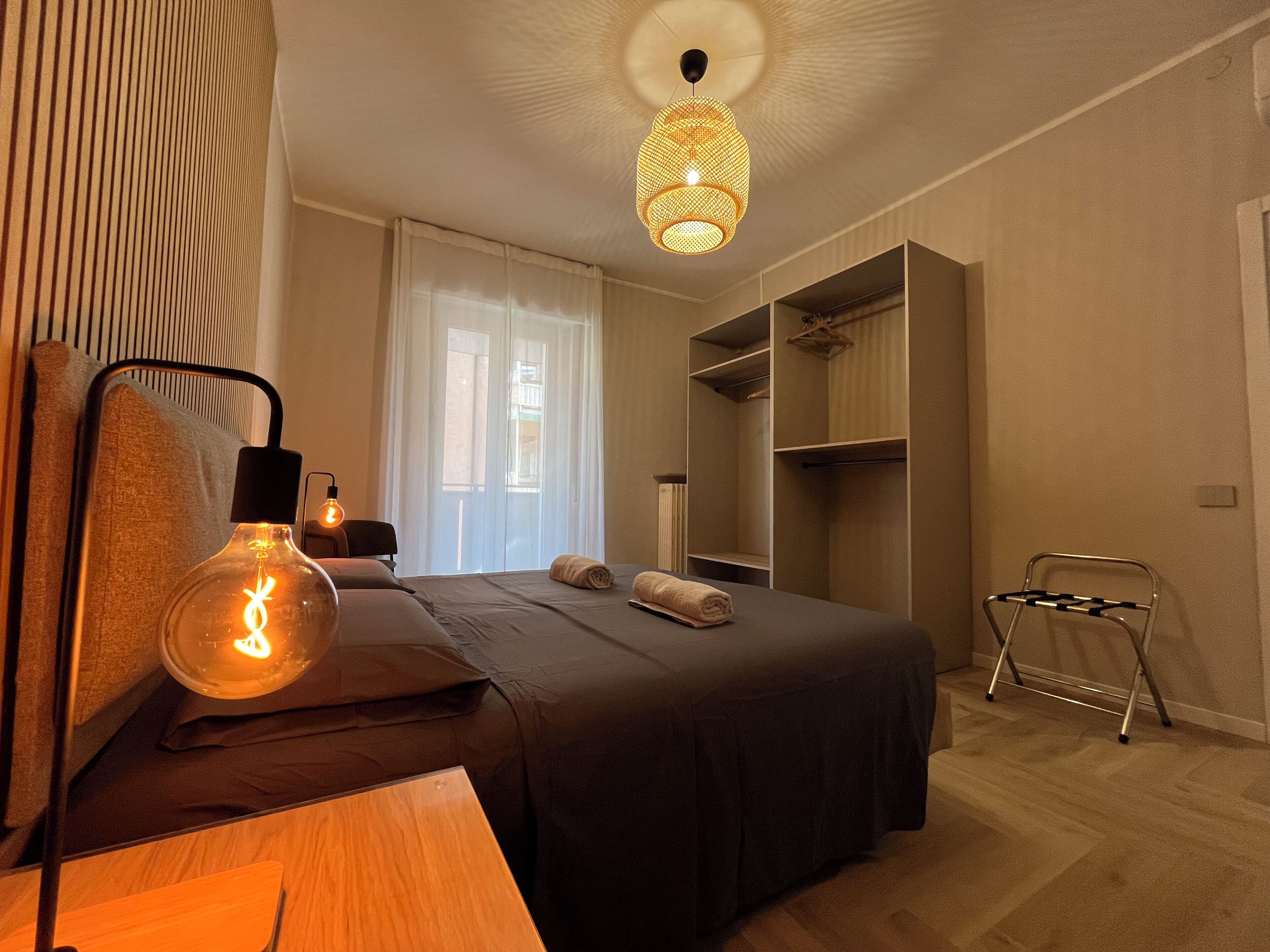 Ein modernes Schlafzimmer mit Bett, Nachttischlampen, einem Kleiderschrank und einem Hängesessel.