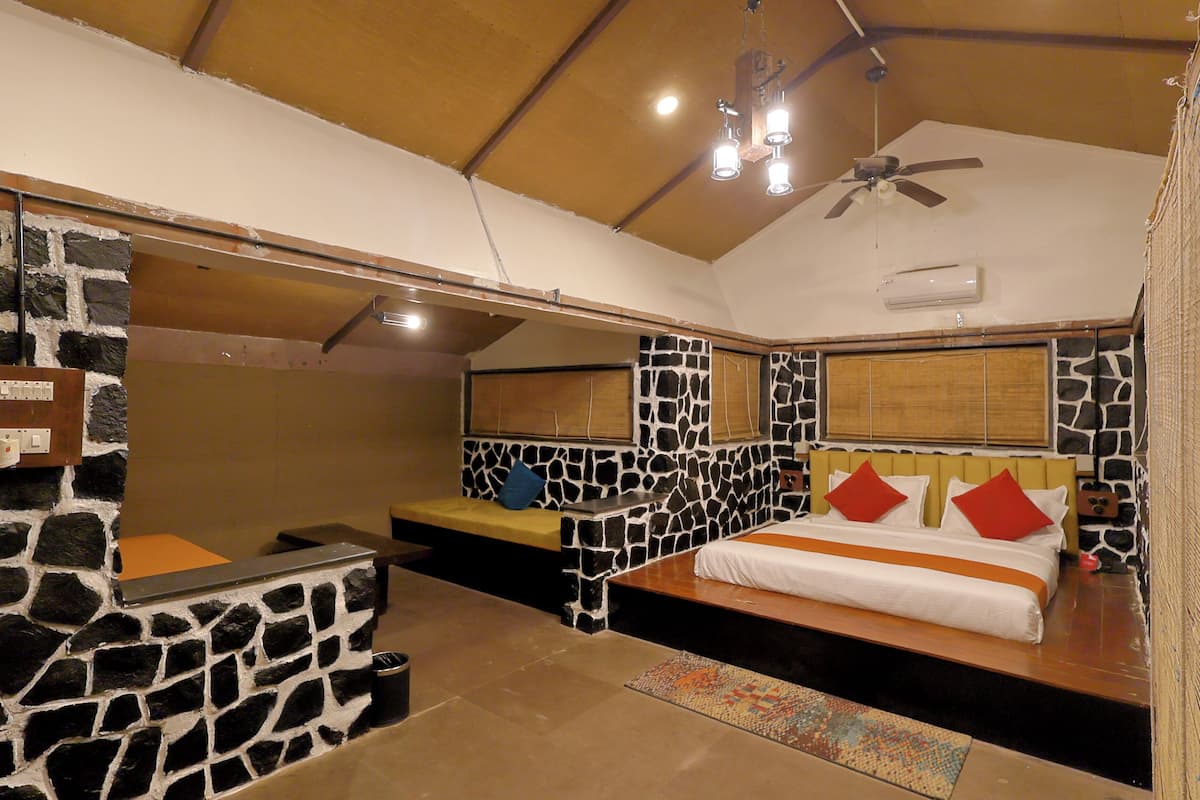 Ein Schlafzimmer mit einer Steinsäule, einem Bett mit roten Kissen, einer Bank und einem Deckenventilator.