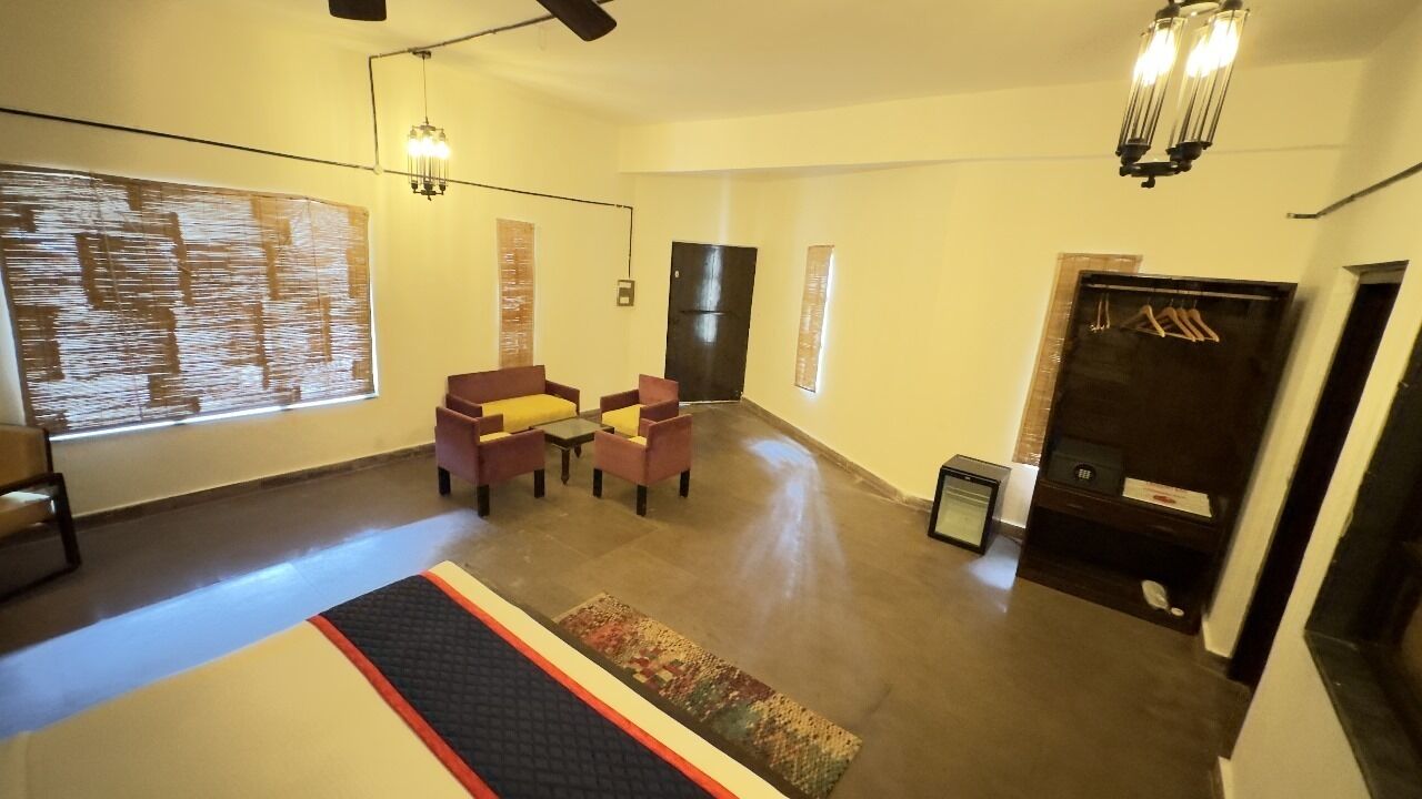 A spacious room with a large window, a sofa, a small table, and a wardrobe.