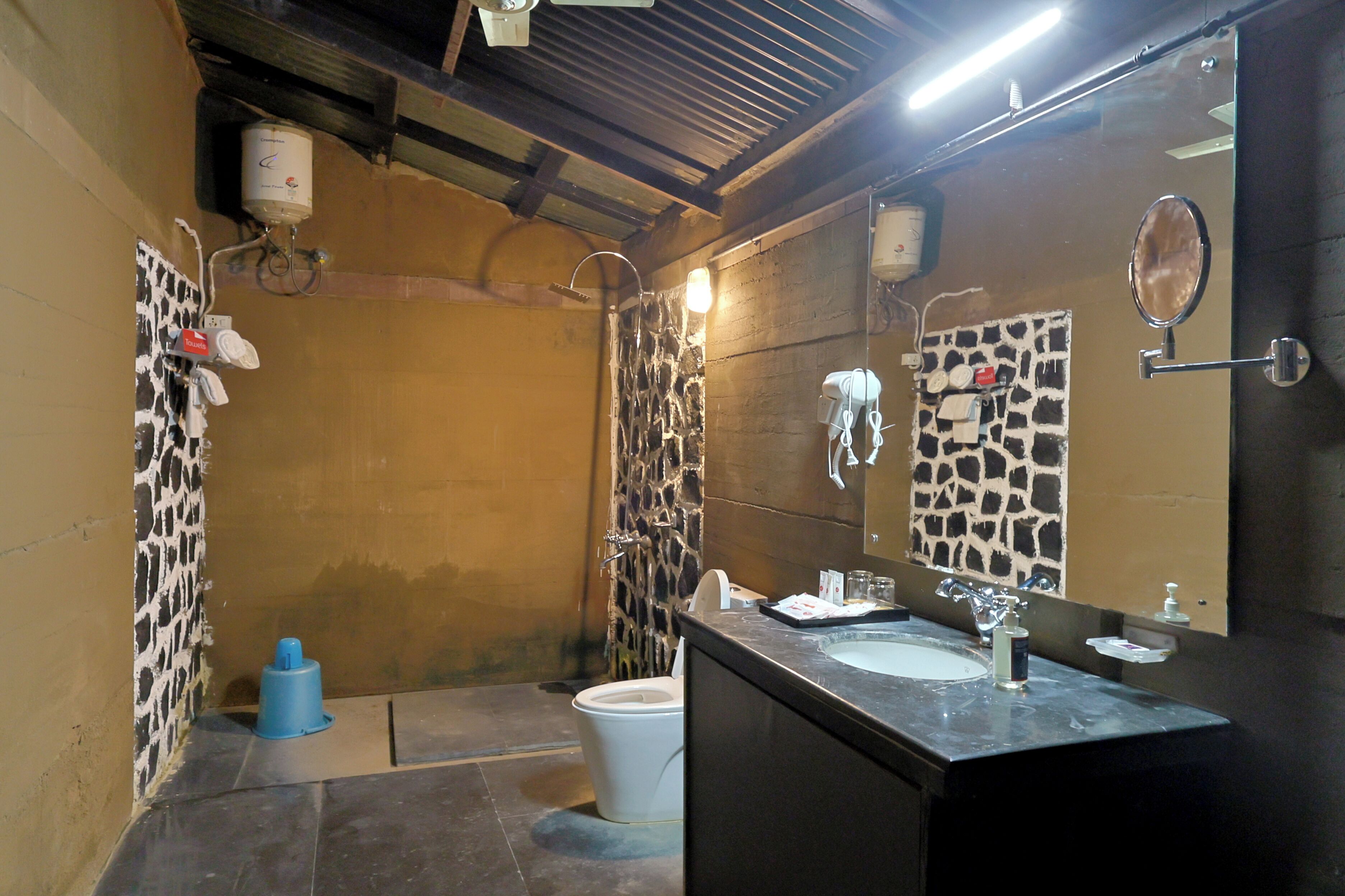 A bathroom with a stone wall, a sink, a mirror, and a shower.