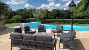 Ett område vid poolen med en pool, utemöbler och en lyktstolpe.
